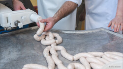 Haut der Weißwürste werden per Hand mit Masse befüllt | © Anna Stoecher