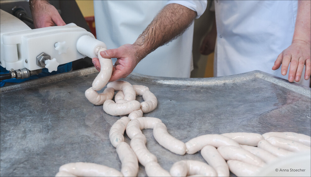 Haut der Weißwürste werden per Hand mit Masse befüllt | © Anna Stoecher