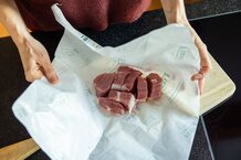 Hände packen Schweinefleisch aus | © Land schafft Leben