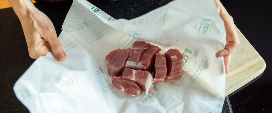 Hände packen Schweinefleisch aus | © Land schafft Leben