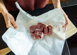 Hände packen Schweinefleisch aus | © Land schafft Leben